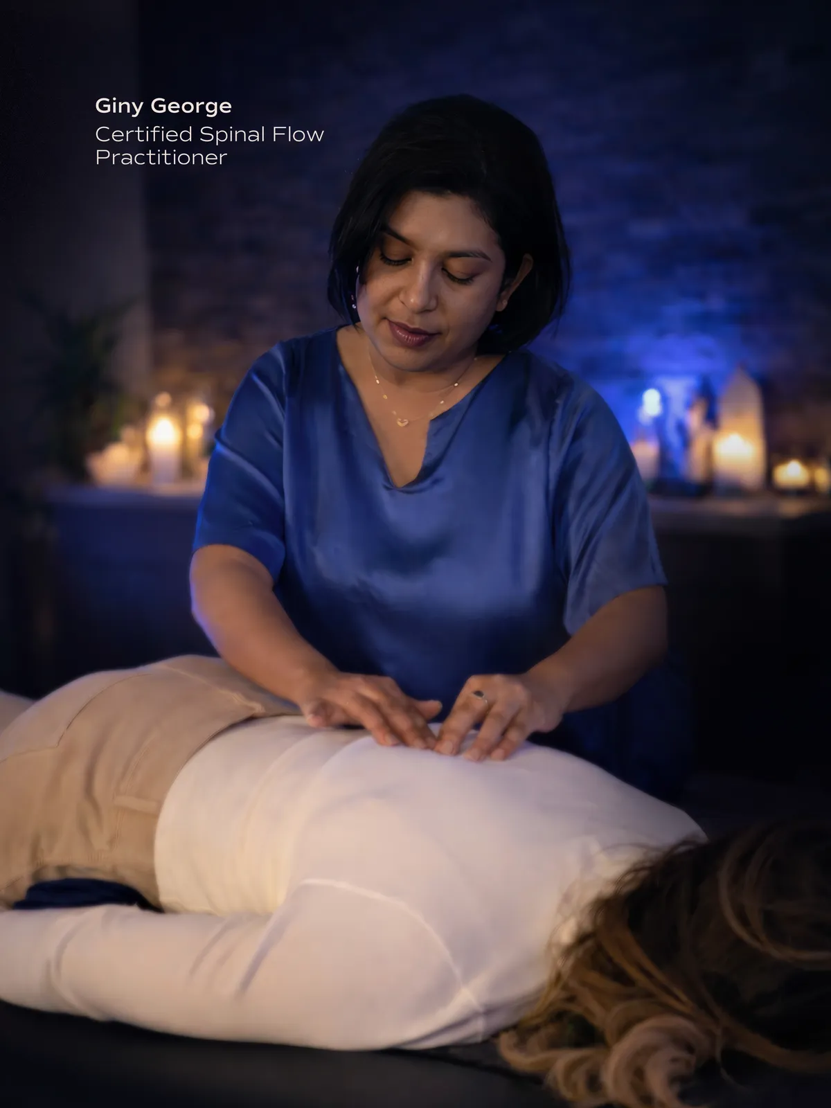 Giny George, Certified Spinal Flow Practitioner, performing a spinal flow therapy session by candlelight